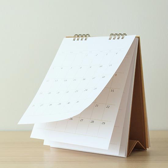 2026 Calendar of Events; A tabletop calendar on a wooden surface with pages slightly fanned open. The image conveys a sense of organization and simplicity.