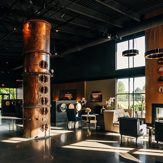 Save the Date! 2026 KTA Annual Membership Conference & Expo; Spacious lounge with industrial decor, featuring a large copper column and modern furniture. Sunlight streams through tall windows, creating a warm ambiance.