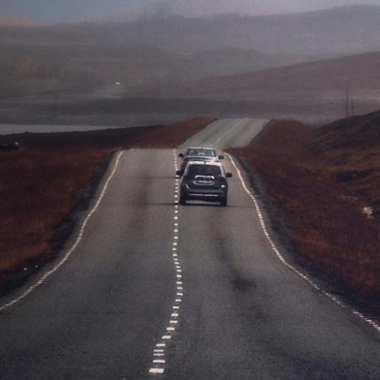 A Plate With Purpose; A foggy road stretches into the distance with two cars heading into the mist. The scene feels calm yet mysterious, with muted tones and a serene atmosphere.